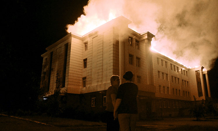 Bystanders watch a fire consuming a school in downtown Donetsk. Picture: Getty