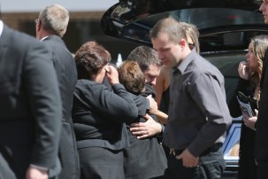 John O'Brien is comforted by mourners at his wife and son's funeral.
