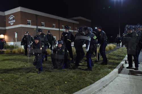 Ferguson police officers take cover from bottles thrown by demonstrators. Photo: Getty