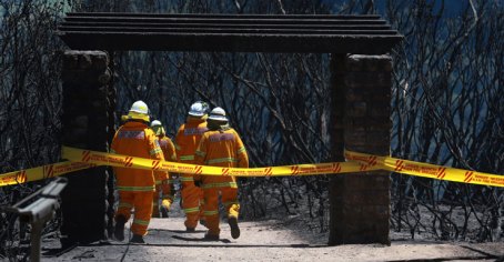 Firefighters inspect the burnt remains of a house at Katoomba