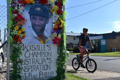 A boy rides his bicycle next to a portrait Hughes in his home town of Macksville. Photo: Getty