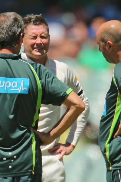 The pain is etched on Michael Clarke's face as Peter Brukner (left) and Alex Kountouris look on. Photo: Getty