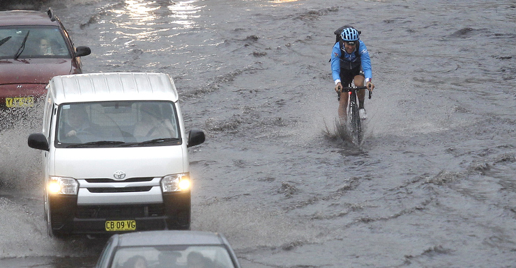 A cyclist powers through a flooded road at Bondi Junction, Sydney.