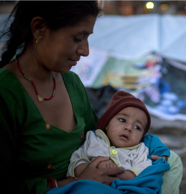 A woman and child sit in the open area in case of an after shock following a second major earthquake