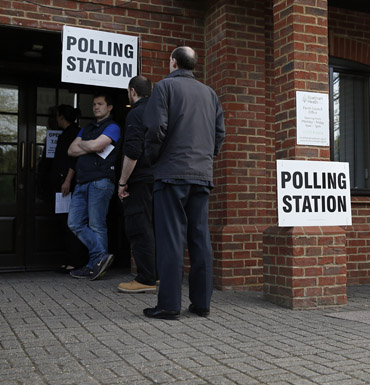 Members of the public wait to cast their votes at a polling station in Elvetham Heath in southern England