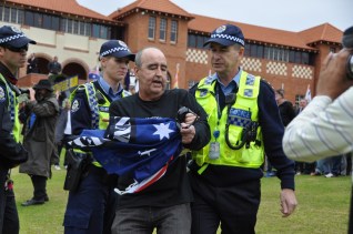 A Reclaim Australia protester is escorted away from the rally in Perth. Photo: AAP