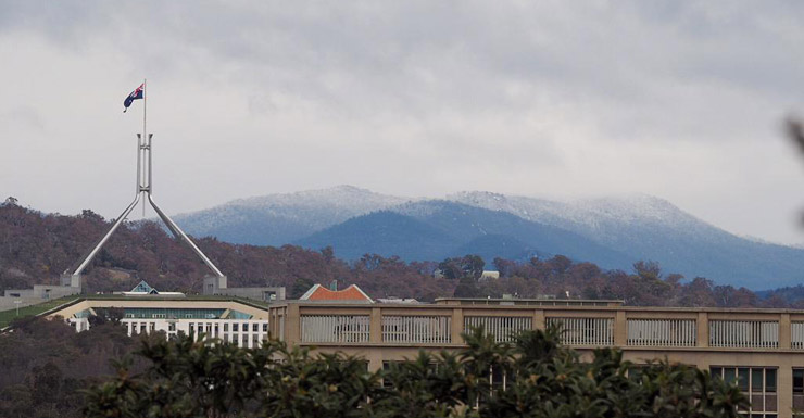 Snow capped mountains in Canberra, with Parliament House in the foreground. 