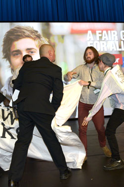 Protesters have their banner removed by security. Photo: AAP
