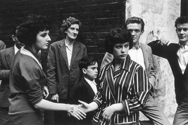 Soho teenagers in typical late 1950s attire of suits, striped jackets and pullovers meet and greet each other on the street Date: 1959