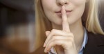 Close up cropped image of young businesswoman with finger on lips
