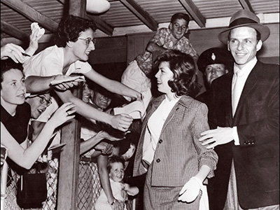 SYDNEY, AUSTRALIA: Legendary US singer Frank Sinatra (r) in a picture taken 21 January 1955 in Sydney arrives with his daughter Nancy14, at the airport while eager fans almost spill over the fence in their efforts to get autographs. Frank Sinatra, born 12 December 1915, was a playboy who married four times, twice to famous actress, Ava Gardner and Mia Farrow. Sinatra's first wife, Nancy Barbato, was his neighborhood sweetheart when he was a struggling young singer from Hoboken, New Jersey. They married in 1939 and had three children, Nancy, Franklin Wayne and Christine. Sinatra caused a scandal when he left his wife and children in 1949 for the US actress Ava Gardner, whom he married in 1951. They divorced and remarried, splitting for a final time in 1957. (Photo credit should read AFP/AFP/Getty Images)