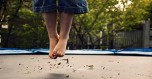 Childs dirty feet jumping on trampoline