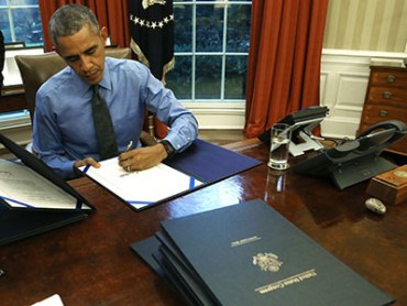 WASHINGTON, DC - DECEMBER 18: U.S. President Barack Obama signs one of 12 bills at his desk in the Oval Office at the White House December 18, 2015 in Washington, DC. Later today President Obama will travel to San Bernardino, California, to meet with families of the 14 victims of the recent mass shooting, before heading to Hawaii for Christmas vacation and return on January 3, 2016. (Photo by Mark Wilson/Getty Images)