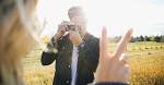 Young man photographing girlfriend gesturing peace sign