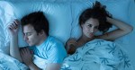 Couple lying together in bed, woman restlessly awake looking away