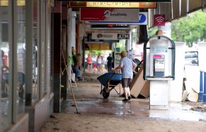 Locals clean debris in the centre town centre as floodwater recedes after the levee broke inundating Lismore