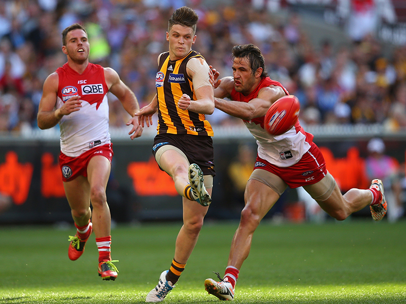 Taylor Duryea of the Hawks kicks whilst being tackled by Josh Kennedy of the Swans during the 2014 AFL Grand Final. Getty