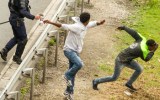 A police officer sprays tear gas onto migrants trying to access the Channel Tunnel in Calais.