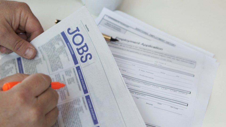 A person searches the paper for a new job.