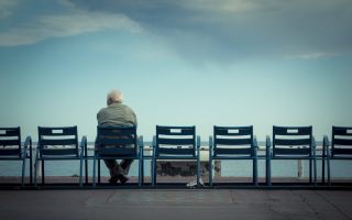 Rear View Of Man Sitting On Chair Against Cloudy Sky - stock photo