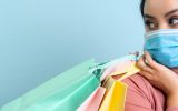 A woman wearing a mask holding shopping bags