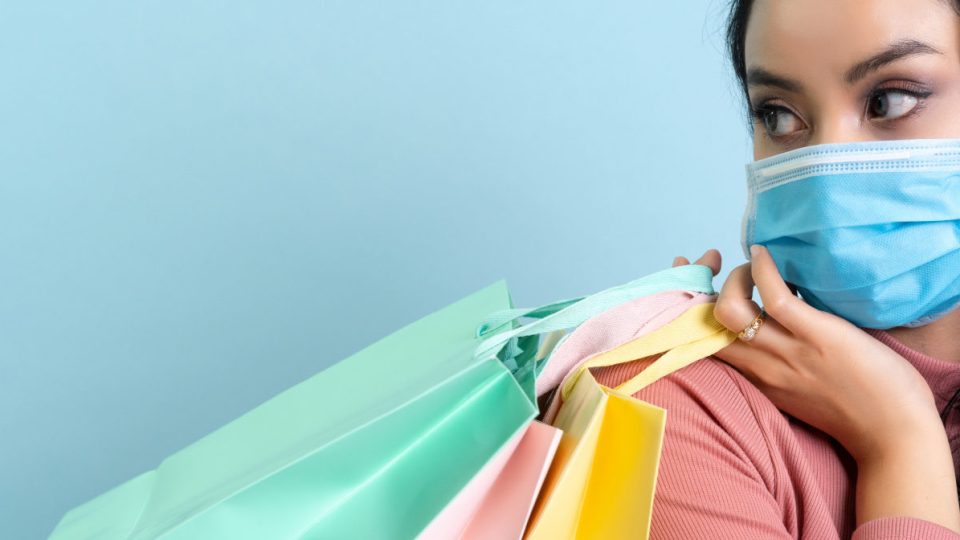 A woman wearing a mask holding shopping bags
