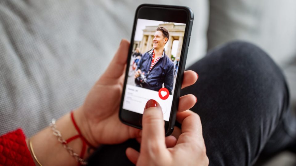 Close-up of a female using a dating app on smart phone. Woman looking at man on an online dating app on her mobile phone