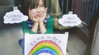 Happy boy sticking his drawings on home window during the Covid-19 crisis