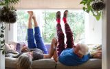 A senior couple lie on the sofa with their legs in the air
