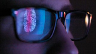 A person in glasses looking at a computer monitor. scammers