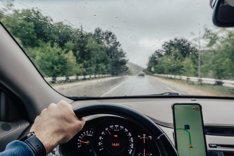Personal perspective of person driving with navigation on road in rainy season