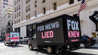 Truck billboards drive in front of the Palace Hotel calling out Fox News' election denial scheme as Fox CEO Lachlan Murdoch attends an event on March 08, 2023 in San Francisco, California